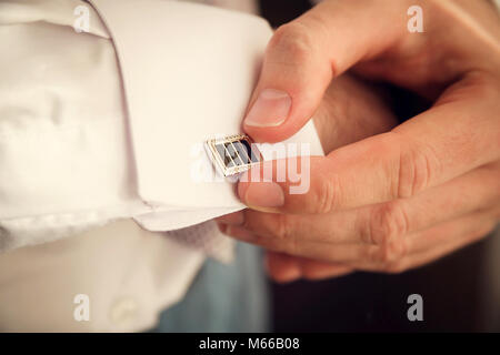 Groom mettant sur boutons de manchettes qu'il s'habille en tenue de cérémonie close up Banque D'Images