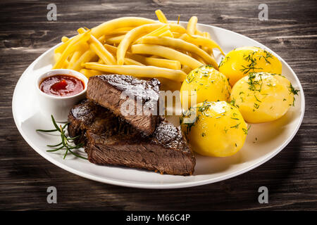 Le steak grillé, pommes de terre et haricots tellow sur table en bois Banque D'Images