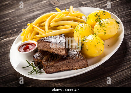 Le steak grillé, pommes de terre et haricots tellow sur table en bois Banque D'Images