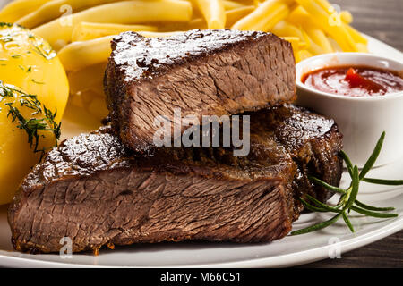 Le steak grillé, pommes de terre et haricots tellow sur table en bois Banque D'Images