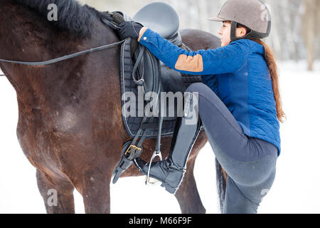 Jeune fille sur son cheval de la baie de montage pour l'équitation. L'approche Banque D'Images