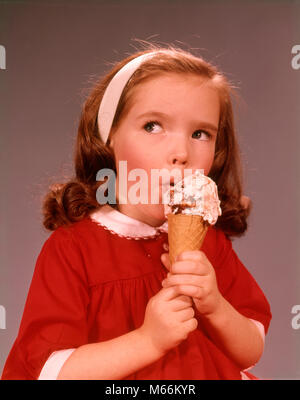 1960 BRUNETTE MIGNON EXPRESSION PETITE FILLE PORTANT UNE ROBE ROUGE EATING ICE CREAM CONE - kf3974 HAR001 HARS, SEUL OBJET DE LÉCHER LE BONHEUR profiter de l'excitation des CÔNES DE CRÈME GLACÉE LA CROISSANCE DES CHEVEUX LONGS jusqu'à lécher les mineurs de l'origine ethnique caucasienne rafraîchissant tourbillon de chocolat à l'ANCIENNE PRODUIT LAITIERS ROBE ROUGE CÔNE DE SUCRE Banque D'Images