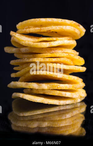 Chips de banane cuite pile libre sur fond sombre reflet sur la surface de verre Banque D'Images