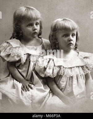 1890 PORTRAIT TOURNANT DU 20ème siècle SŒURS JUMELLES identiques portant des robes et montrant des expressions du visage triste MOROSE - o4472 HAR001 HARS NOSTALGIE TRISTESSE UNITÉ 1-2 ans 3-4 ans correspondant à même TOUR DE LA 20e siècle années 1890, SŒUR ANONYME CONNEXION EN DOUBLE À L'APPARENCE ÉMOTIONNELLE ÉMOTION ÉMOTIONS JUVÉNILES SE RESSEMBLENT B&W NOIR ET BLANC DE L'ORIGINE ETHNIQUE CAUCASIENNE MOROSE CLONE DÉMODÉ Banque D'Images