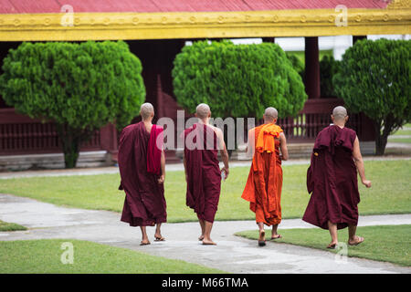 Quatre jeunes moines à pied à l'intérieur du complexe du Palais Royal de Mandalay, Myanmar (Birmanie). Banque D'Images