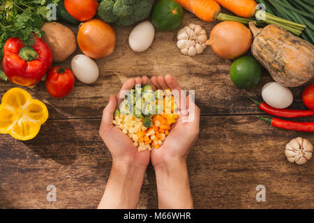 Légumes hachés sur les mains et le chef de cuisine végétarienne ingrédients savoureux. Vue d'en haut. Banque D'Images