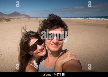 Faire place au jeune couple heureux portrait à la plage. Medium close-up avec arrière-plan panoramique. Fuerteventura, îles Canaries, Espagne. Banque D'Images