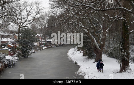 Les gens marchent à côté d'un canal près de Basingstoke congelé à Brookwood à Surrey, en tant que tempête Emma, roulant en provenance de l'Atlantique, semble prêt à affronter la bête de l'est fait froid la Russie - de l'air généralisée à l'origine de nouvelles chutes de neige et températures amer. Banque D'Images