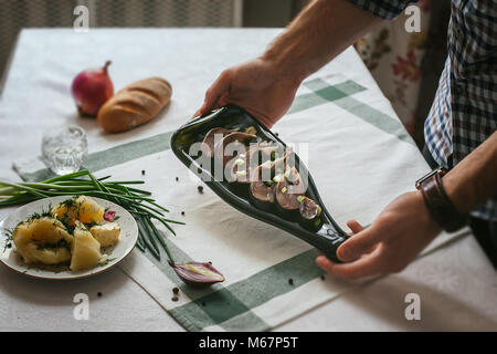 Seulement les mains. L'homme termine son assiette et presque prêt à servir à la table. Décoration de la table. Plats de service. Manger dans de beaux plats. Russi Banque D'Images