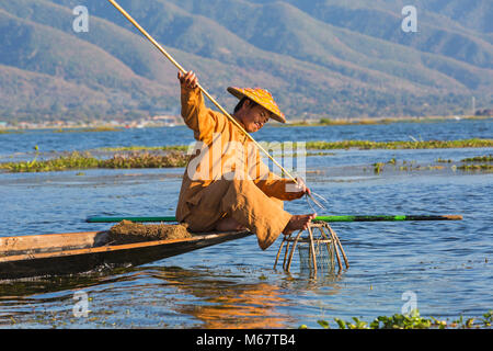 Intha leg rameur pêcheurs à Shan State, Inle Lake, Myanmar (Birmanie), Asie en février - pêcheur assis sur un bateau tenant la lance dans les mains Banque D'Images