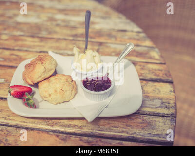 Vintage photo de filtré avec un thé à la crème et de la confiture de scone sur une table Banque D'Images