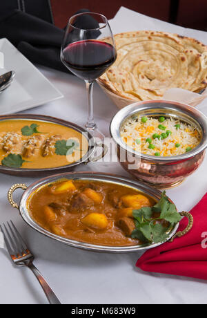 Aliments curry indien étendu sur une table de dîner de fantaisie avec du riz, de l'laccha, agneau Paratha Placez aam wala, safran malai kofta, vin rouge. Banque D'Images
