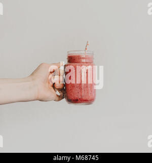Personne méconnaissable holding jar potable avec smoothie rouge. Banque D'Images