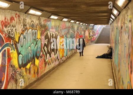 Sans-abri mendier de l'argent dans un tunnel de métro couverts de graffitis Banque D'Images