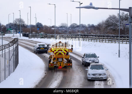 Sel de grain répandant des grinds sur une route couverte de neige avec des voitures pendant la bête du phénomène météorologique de l'est Banque D'Images