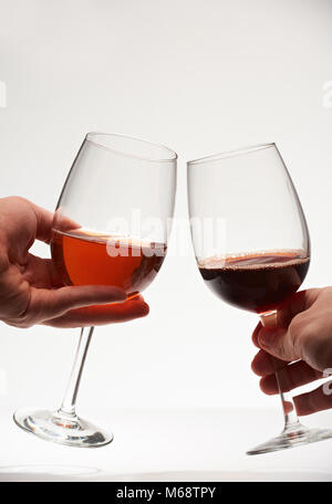 Deux verres de vin rouge dans les mains. Toast romantique isolé sur fond blanc Banque D'Images