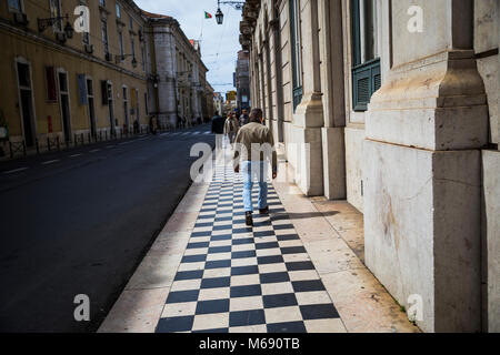 Un homme marche à l'arrivée des tuiles dans Lisbonne, Portugal. Banque D'Images