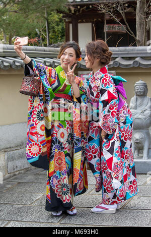 Deux jeunes filles de prendre un qui ont engagé des selfies costumes traditionnels japonais sont représentés dans la région de Kyoto, au Japon, près de la Temple Kiyomizu-dera. Banque D'Images