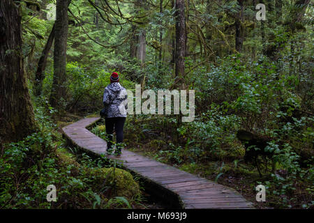 Jeune fille portant un veston rouge est la marche de la magnifique forêt en une matinée d'hiver. Prises à Ucluelet, île de Vancouver, BC, Canada. Banque D'Images