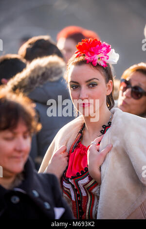 PERNIK, BULGARIE - 26 janvier 2018 : Beautiful Girl dancer avec des fleurs dans ses cheveux détient son manteau et regarde pensivement dans la journée d'hiver ensoleillée à I Banque D'Images