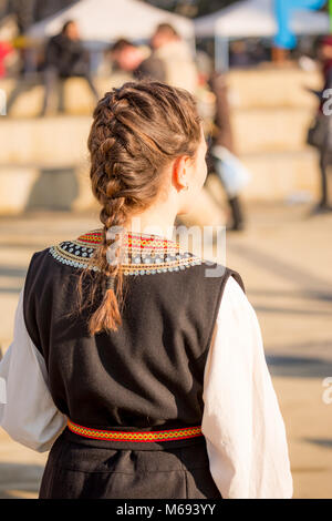 PERNIK, BULGARIE - 26 janvier 2018 : danseuse en costume folklorique bulgare montre montre fièrement sa chambre en y hairstyle dans d'hiver ensoleillée journée à la Banque D'Images