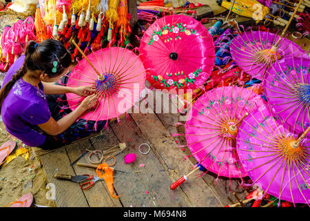 Une femme est la fabrication d'un des parapluies, parasols colorés, en bambou et tissu, dans un petit atelier Banque D'Images