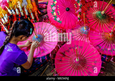 Une femme est la fabrication d'un des parapluies, parasols colorés, en bambou et tissu, dans un petit atelier Banque D'Images