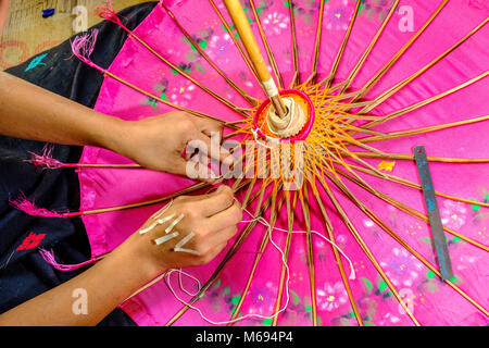 Une femme est la fabrication d'un des parapluies, parasols colorés, en bambou et tissu, dans un petit atelier Banque D'Images