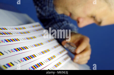 Test d'impression CMJN le contrôle et l'immatriculation sur l'imprimé. L'homme à l'aide de lentille loupe pour contrôler la qualité. Banque D'Images