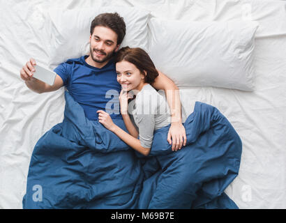 Jeune couple en vue de dessus de lit concept matin mari prendre des photos Banque D'Images