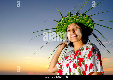 Portrait of a smiling belle jeune femme portant un chapeau fabriqué à partir de leafes palm, le Thanaka et coller la face jaune Banque D'Images