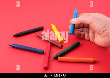 Certains crayons de cire colorée sur une surface rouge Banque D'Images