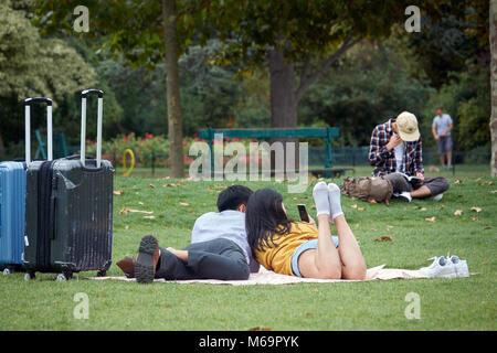 Asian couple dans l'amour se trouve sur l'herbe et rend vos autoportraits sur le Champ de Mars à Paris. Banque D'Images