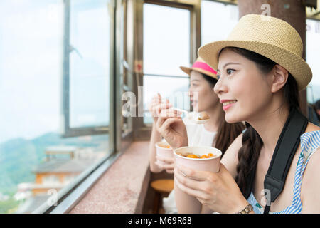 Heureux deux femmes asiatiques ont profiter de tourisme local food célèbres boules de taro dans la ville de Taipei Jiufen, looking out great ocean vue depuis le haut de la colline. Banque D'Images