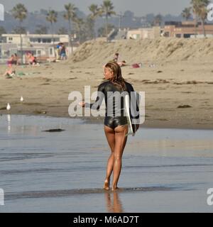 Beau et bon surfeur femme Latino en néoprène et de marcher à Mission Beach, San Diego, Californie, USA. Banque D'Images