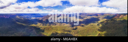 Bleu majestueux des montagnes de l'Australie sur un jour d'été ensoleillé avec la lumière à tomber sur des rochers de grès et ses environs canyon avec evergreen gommiers. Banque D'Images