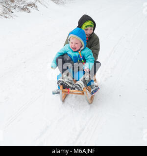 Garçon de huit ans et son frère âgé de 18 mois. La luge ou de la luge dans la neige , Medstead, Alton, Hampshire, Angleterre, Royaume-Uni. Banque D'Images