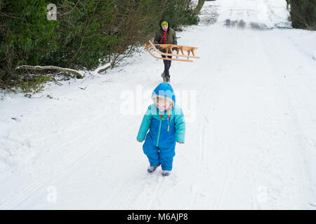 Garçon de huit ans et son frère âgé de 18 mois. La luge ou de la luge dans la neige , Medstead, Alton, Hampshire, Angleterre, Royaume-Uni. Banque D'Images