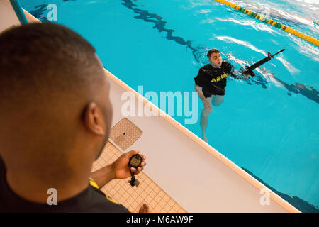 Un soldat américain fois Sgt. Jacobus de bois, avec la Police militaire de Bruxelles à la U.S. Army Garrison Benelux, qu'il nage tout en gardant la plupart de ses armes hors de l'eau au cours de la garnison's Best Warrior la concurrence dans la piscine du Grand Quartier général des Puissances alliées en Europe, Belgique, le 21 février 2018. (U.S. Army Banque D'Images