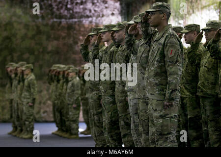 Des soldats de la 1ère Division d'infanterie américaine, à Fort Riley, Kansas et 4e Division d'infanterie américaine, Fort Carson, Colorado, militaires durant la lecture de l'hymne national américain lors d'une cérémonie de transfert d'autorité à Poznan, Pologne, le 28 février 2018. Banque D'Images