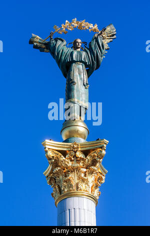 Libre sculpture en bronze de jeune fille ukrainienne avec golden garland sur la colonne de l'Indépendance à Kiev contre le ciel bleu Banque D'Images