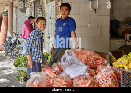 Kashan, Iran - avril 27, 2017 : Deux adolescents sont debout près de sacs avec carottes fraîches dans un magasin de légumes. Banque D'Images