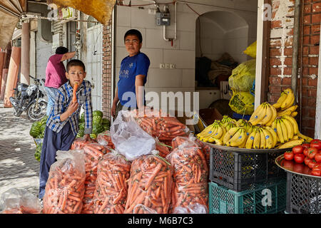 Kashan, Iran - avril 27, 2017 : Deux adolescents se tenir près de la sacs de carottes fraîches dans le magasin de légumes. Banque D'Images