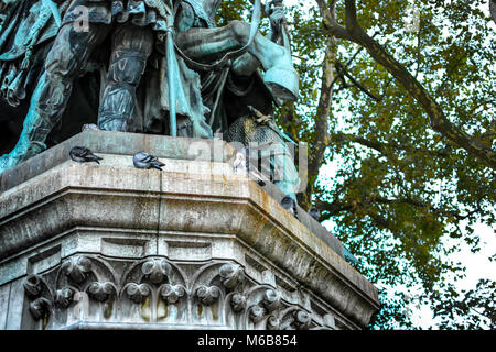 Un pigeon blanc et plusieurs autres pigeons sombre se perchent sur la statue de Charlemagne avec son cheval sur la place de la Cathédrale Notre Dame Paris France Banque D'Images