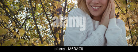 Image composite de portrait of smiling woman wearing sweater with hands clasped Banque D'Images