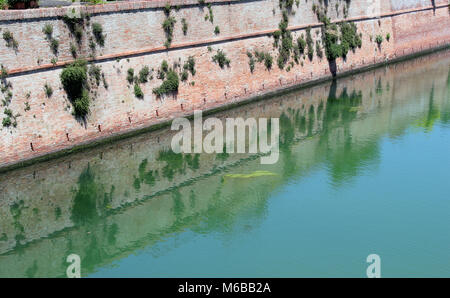 Diagonale d'une vieille ville sale river. Le remblai est fait de briques en argile rouge. Paysage d'été ensoleillée journée Juin Banque D'Images