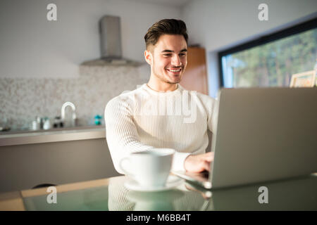 Portrait de jeune homme heureux le travail à domicile sur ordinateur portable Banque D'Images