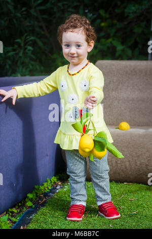 Redhead girl robe jaune en offrant des citrons Banque D'Images