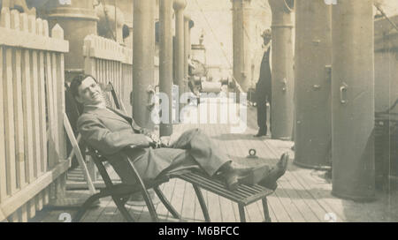 Photographie, c1900 Antique man reclining on deck chair à bord d'un navire à vapeur. Banque D'Images