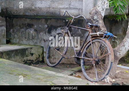 Vieux vélo stationné près de mur de pierre en Asie. Banque D'Images